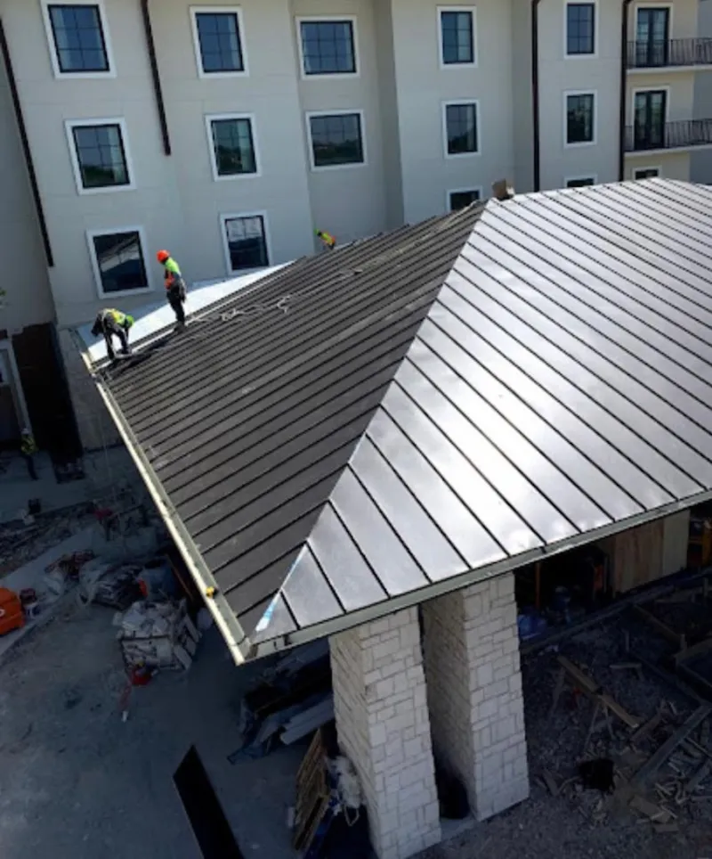 Crew installing standing seam metal roof panels on a commercial project in Canton